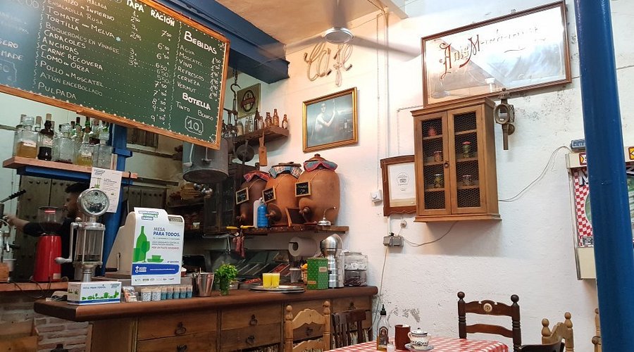 Traditional interior of La Recova café in Málaga with rustic décor, handmade baskets, and locals enjoying breakfast and brunch