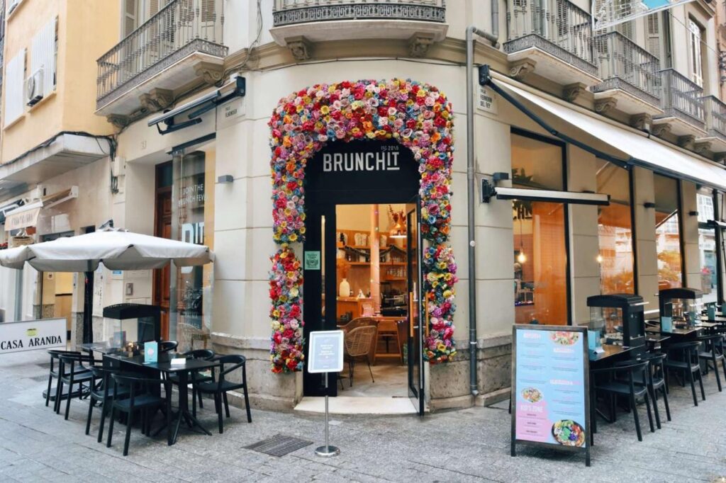 Brunchit Málaga entrance with colorful flower facade in city center – best brunch Málaga location