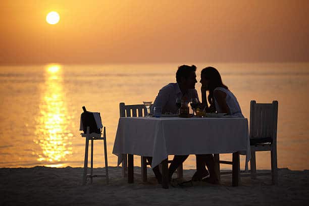 A young couple gazing into each other's eyes while having dinner on the beach