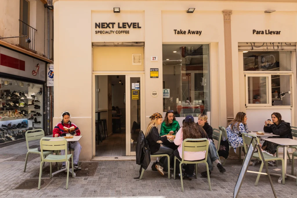 Next Level Specialty Coffee Málaga exterior with outdoor seating and customers enjoying coffee