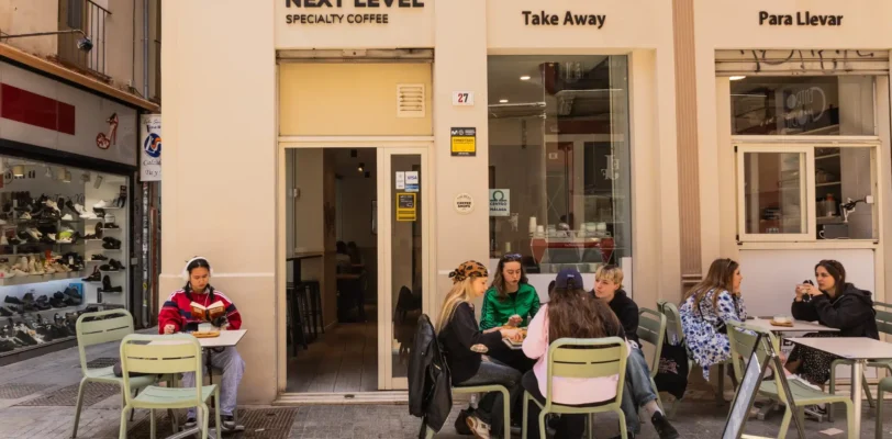 Next Level Specialty Coffee Málaga – Außenansicht mit Sitzgelegenheiten im Freien und Kunden, die Kaffee genießen